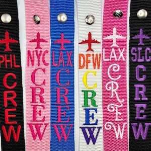 May include: Set of 8 colorful luggage tags with the word "CREW" embroidered in white, pink, blue, yellow, white, pink, purple, and blue. Each tag has a different airport code: MSP, PHL, NYC, LAX, DFW, LAX, SLC, TPA.