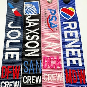 May include: Four blue, black, pink, and blue luggage tags with white text and logos. The tags read "Jolie DFW Crew", "Jaxson SAN Crew", "Kay DCA Crew", and "Renee MDW Crew".