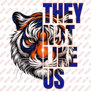 May include: A graphic design featuring a tiger's face with orange, blue, and white stripes. The text "THEY NOT LIKE US" is overlaid in blue and orange, creating a bold and eye-catching design.