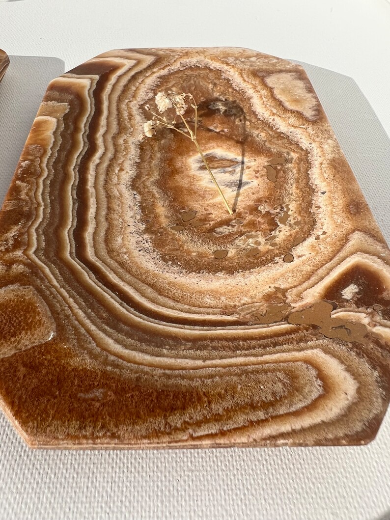 May include: A brown and white onyx serving tray with a decorative, wavy pattern. The tray has a slightly irregular shape and a smooth, polished surface.