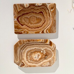 May include: Two rectangular onyx trays with a brown and white swirl pattern. The trays are made of natural stone and have a smooth, polished finish.