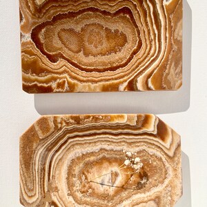 May include: Two rectangular onyx trays with a brown and white swirl pattern. The top tray is a simple rectangle, while the bottom tray has slightly rounded corners.
