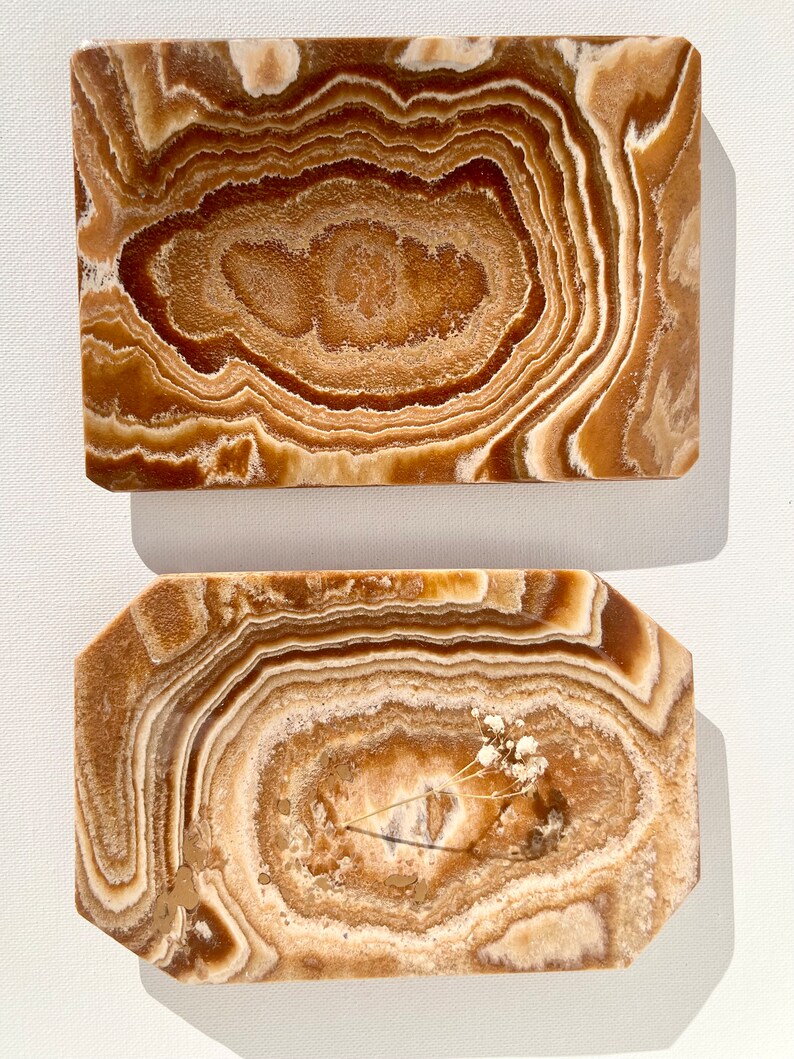 May include: Two rectangular onyx trays with a brown and white swirl pattern. The top tray is a simple rectangle, while the bottom tray has slightly rounded corners.