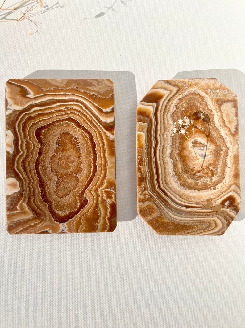 May include: Two rectangular decorative trays made of brown and white onyx with a swirling pattern.