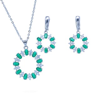 May include: A silver necklace and earrings set with a circular pendant and matching earrings. The pendant and earrings are adorned with green oval-shaped stones and smaller white stones.