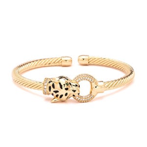 May include: Gold-toned cuff bracelet featuring a leopard head with black spots and a diamond-studded ring clasp. The bracelet has a twisted rope design and is open at the ends.