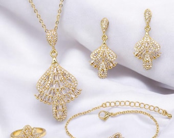 May include: A gold-tone jewelry set with a necklace, earrings, and bracelet. Each piece features a delicate, fan-shaped design with clear cubic zirconia stones.