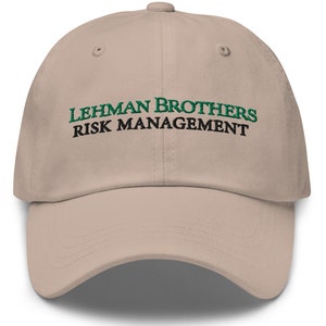 Könnte beinhalten: Eine beige Baseballkappe mit dem Text "LEHMAN BROTHERS RISK MANAGEMENT" in Schwarz und Grün gestickt.
