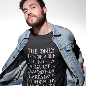 Puede incluir: Camiseta negra con texto blanco: "THE ONLY HONORABLE THING A TARGARYEN CAN DO FOR THIS REALM IS FINISH ON HIS WIFES TITS." La persona lleva una chaqueta vaquera azul.