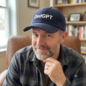 May include: A navy blue corduroy baseball cap featuring the text DadGPT embroidered in white lettering on the front panel. The cap has a structured crown, a curved brim, and a fabric strap closure at the back for an adjustable fit.