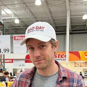 以下が含まれることがあります： 黒い持ち手と「But First, Coffee」の手書き風の文字が入った白いセラミックマグカップ。白い表面に置かれています。マグカップの高さは約10cmです。