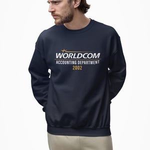 以下が含まれることがあります： 白と金色の「WORLDCOM ACCOUNTING DEPARTMENT 2002」の文字が入った、ネイビーブルーのクルーネックのトレーナー。 トレーナーは人が着ています。