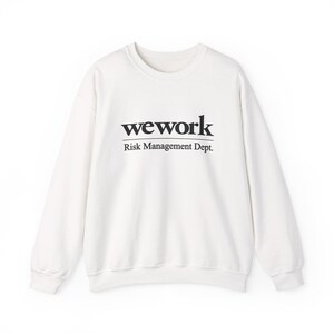 Peut inclure: Un sweat-shirt blanc à col rond avec le texte noir "wework" et "Risk Management Dept." imprimé sur le devant. Le sweat-shirt a des manches longues et des bords-côtes.