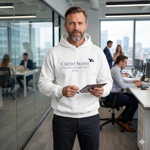 Op de afbeelding: Een witte hoodie met de marineblauwe tekst "CREDIT SUISSE RISK MANAGEMENT DEPT. 2023". De hoodie heeft een capuchon met trekkoord en een voorzak. De persoon houdt een tablet en een stylus vast.