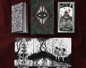 May include: A tarot deck with a black and white aesthetic. The deck includes a guidebook and several cards featuring illustrations of an eye, a house with the word "MIDNIGHT", and other symbolic imagery. The cards are arranged on a dark red surface.