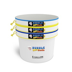 May include: A white 5-gallon bucket with three stacked mesh bags. Each bag has a blue and yellow trim and the text "BUBBLE BAG Dude". The bags have labels with the numbers 25, 73, and 220. Yellow drawstrings are visible.
