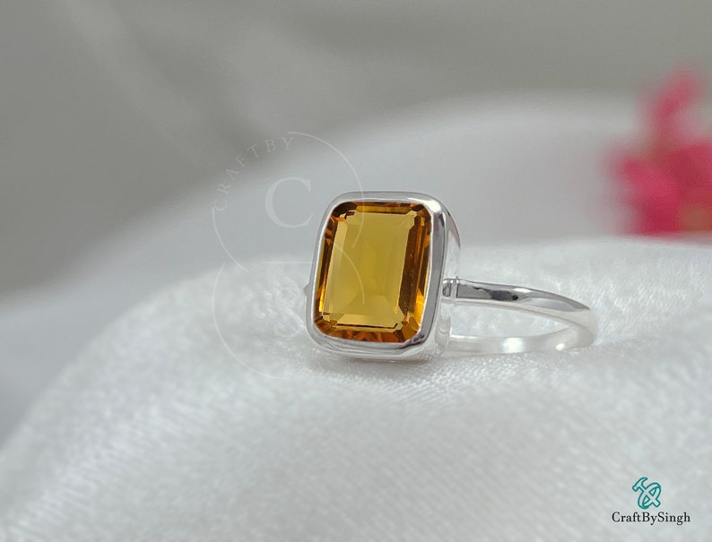 May include: A silver ring with a square-shaped, orange-brown gemstone.