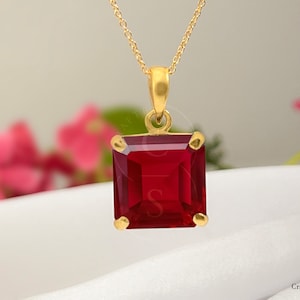Może przedstawiać: Złoty łańcuszek z naszyjnikiem z dużym, kwadratowym, czerwonym kamieniem szlachetnym.