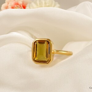 May include: A gold ring with a large, rectangular, yellow-brown gemstone set in a bezel setting.