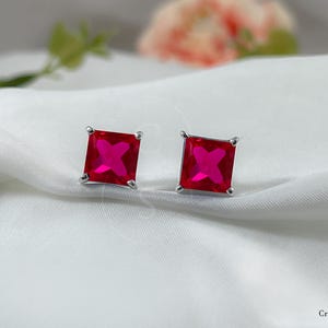 Pode incluir: Um par de brincos de prata com pedras quadradas de zircônia cúbica vermelha.