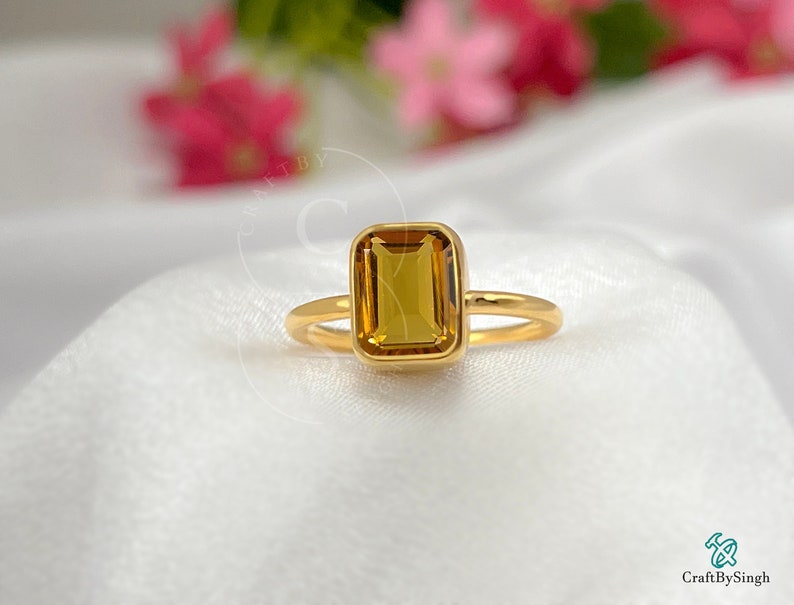 May include: A gold ring with a square-shaped, yellow citrine gemstone.