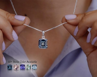 Puede incluir: Un collar de plata con un colgante de piedra preciosa azul de corte cuadrado en una cadena fina. Debajo del colgante, el texto 10+ Stone Color Available aparece junto a cinco pequeños iconos de piedras cuadradas en azul, rosa, morado, verde y azul claro.