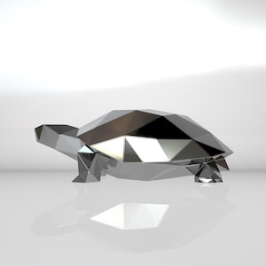 Può includere: Una scultura di tartaruga in argento, geometrica, in stile origami. La scultura è realizzata con molti piccoli pezzi triangolari che si uniscono per creare una tartaruga dall'aspetto realistico.