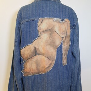 Peut inclure: Une veste en jean bleue avec une figure nue peinte au dos.