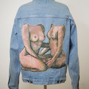 May include: A light blue denim jacket with a painted design of two nude figures on the back.
