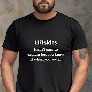 May include: A black t-shirt with white text that reads "Offsides It ain't easy to explain but you know it when you see it."