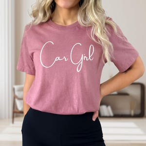 K&ouml;nnte beinhalten: Staubrosa T-Shirt mit dem kursiven Text "Car Girl" in Wei&szlig;. Das kurz&auml;rmelige Shirt ist aus einem weichen Material gefertigt und eignet sich f&uuml;r Freizeitkleidung. Das Shirt wird mit schwarzen Leggings kombiniert.