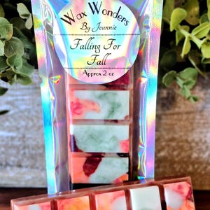 May include: A package of wax melts with a holographic iridescent finish. The label reads "Wax Wonders by Jeannie Falling For Fall Approx 2 oz." The wax melts are rectangular, with a mix of orange, red, and green colors.