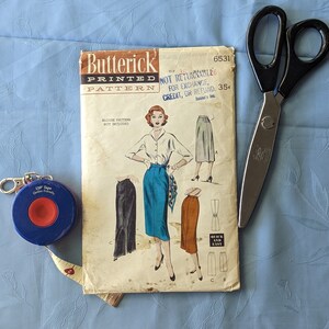 May include: A vintage sewing pattern for a skirt, featuring a woman wearing a blue skirt and a white blouse. The pattern is from Butterick and is labeled "Printed Pattern" and "Quick and Easy".