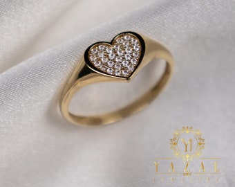 Könnte beinhalten: Ein goldener Ring mit einem herzförmigen Design. Das Herz ist mit kleinen, klaren Steinen besetzt.