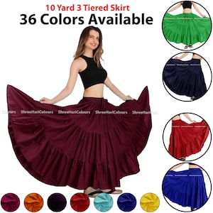 Op de afbeelding: Een vrouw poseert met een bordeauxrode 10-yard, 3-laags rok. De rok is vol en vloeiend, met een brede zoom. De afbeelding toont de rok ook in groen, marineblauw, rood en blauw. Tekst bovenaan luidt "10 Yard 3 Tiered Skirt" en "36 kleuren beschikbaar."