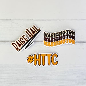May include: Three stickers with a college sports theme. The first sticker is yellow and black and says "Raise Hail". The second sticker is brown and yellow and says "WASHINGTON" three times. The third sticker is yellow and says "#HTTC".