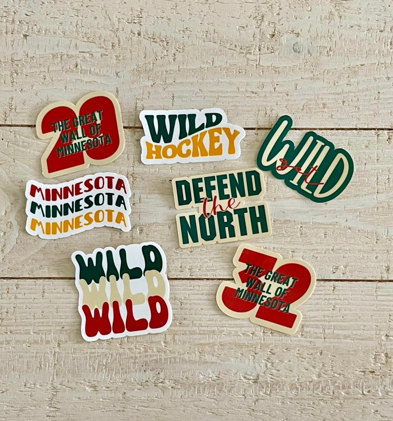 May include: A collection of colorful stickers with text related to Minnesota and hockey. The stickers feature phrases like "Wild Hockey," "Defend the North," and "The Great Wall of Minnesota." The color palette includes green, red, yellow, and white.