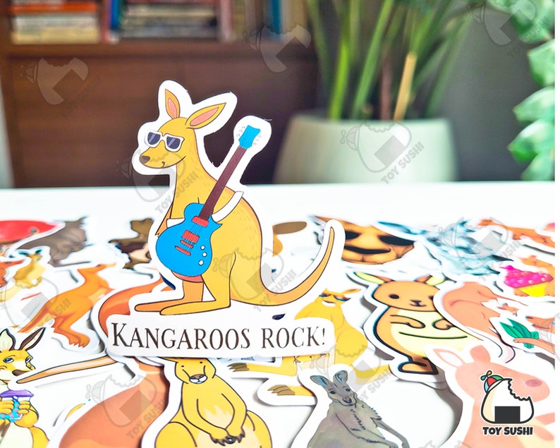 May include: A collection of colorful stickers featuring kangaroos, some playing musical instruments. One sticker shows a kangaroo playing a blue electric guitar with the text "Kangaroos Rock!"