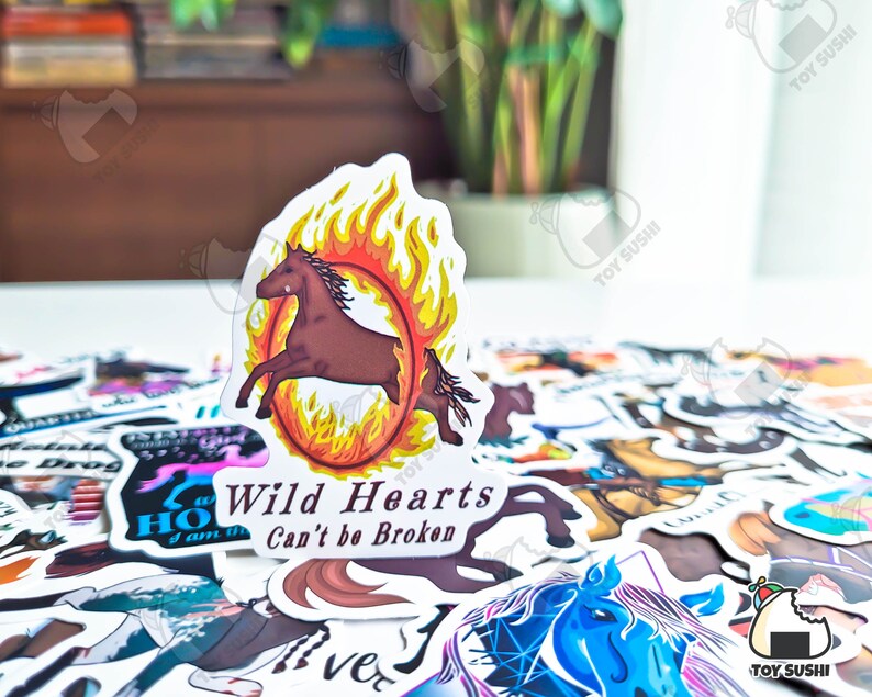 May include: A sticker with a brown horse running in a circle of fire. The sticker has the text "Wild Hearts Can't be Broken" on it.