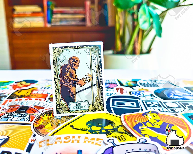 May include: A sticker featuring a skeletal figure welding, with the text "The Welder" in a decorative frame. The sticker is surrounded by other colorful stickers with various designs and text, including welding-related imagery.
