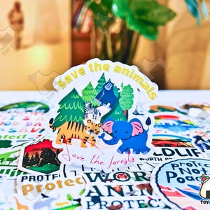 May include: A colorful sticker with a cartoon tiger, elephant, and monkey in a forest setting. The sticker says "Save the animals" and "Save the forests".