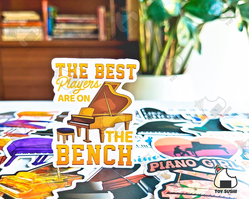 May include: A sticker with a yellow and brown piano and the text "The Best Players Are On The Bench".