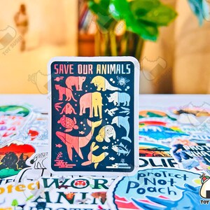 May include: A colorful sticker with the text "Save Our Animals" and illustrations of various animals, including a whale, a turtle, a bear, and a rhinoceros. The sticker is surrounded by other stickers with various designs.
