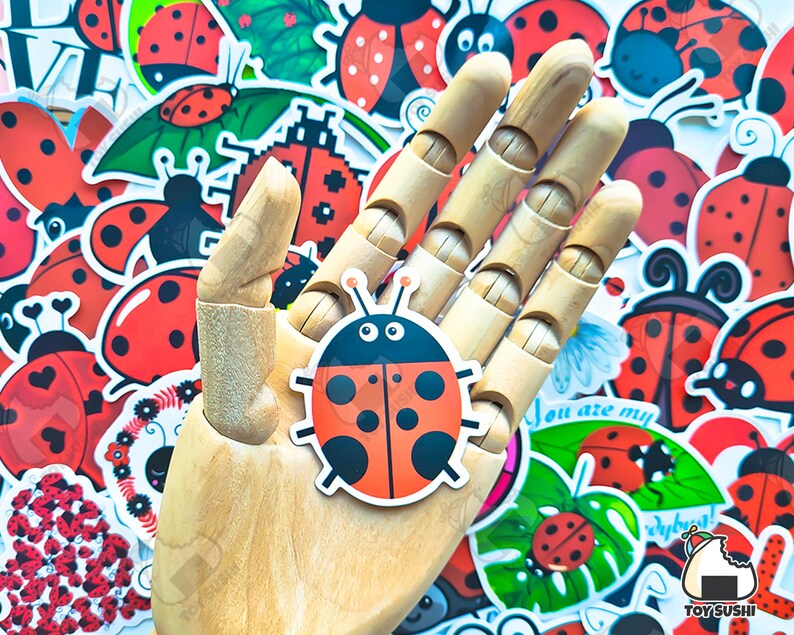 May include: A wooden hand holding a red and black ladybug sticker. The sticker has white spots and black eyes. The hand is surrounded by a variety of ladybug stickers in different designs and colors.