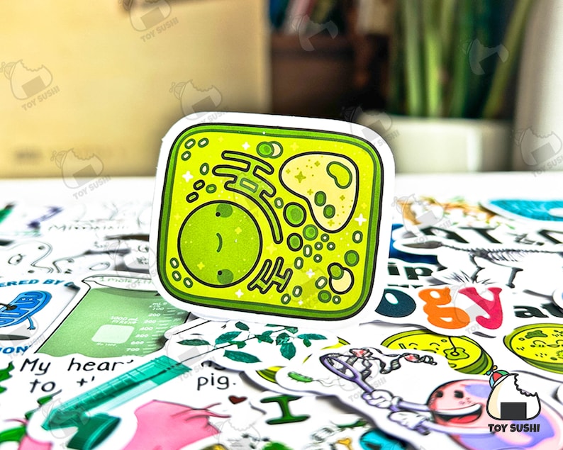 Puede incluir: Una pegatina verde y amarilla con un diagrama de c&eacute;lula de dibujos animados. La pegatina tiene un borde blanco e incluye varios componentes celulares. La pegatina est&aacute; rodeada de otras pegatinas con temas relacionados con la ciencia.