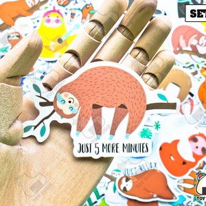 May include: A set of colorful sloth stickers with various designs. One sticker features a sloth hanging from a branch with the text "Just 5 more minutes". The set is labeled "Set B".
