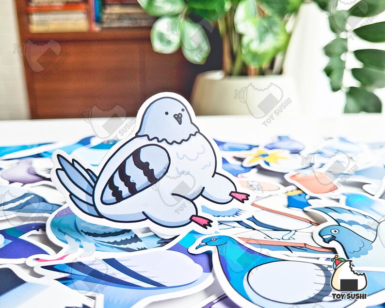 May include: A collection of colourful cartoon bird stickers, including a blue pigeon with black stripes, a blue bird with a long neck, and a white bird with a black beak. The stickers are on a white surface.