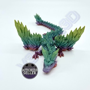 Puede incluir: Una figurita de dragón de cristal verde, morado y rojo con una superficie texturizada detallada.