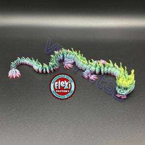 Puede incluir: Una figurita de dragón verde, morado y amarillo iridiscente con una cabeza y escamas detalladas. El dragón está enroscado en una posición de descanso. La imagen también incluye una pegatina roja y blanca que dice "Authorized Seller Flexi Factory Authorized Seller".