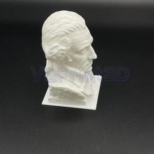 May include: White 3D printed bust of a man with a short, wavy hairstyle. The bust is on a white base.